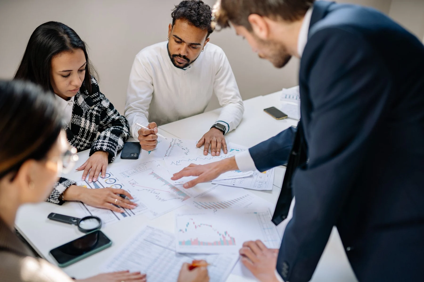 A team reviews printed charts together around a table.
