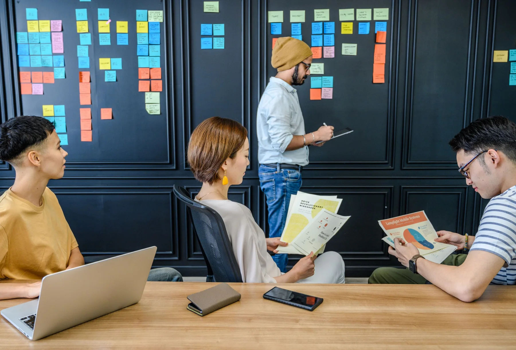 Colleagues work together around a planning board in a workshop.