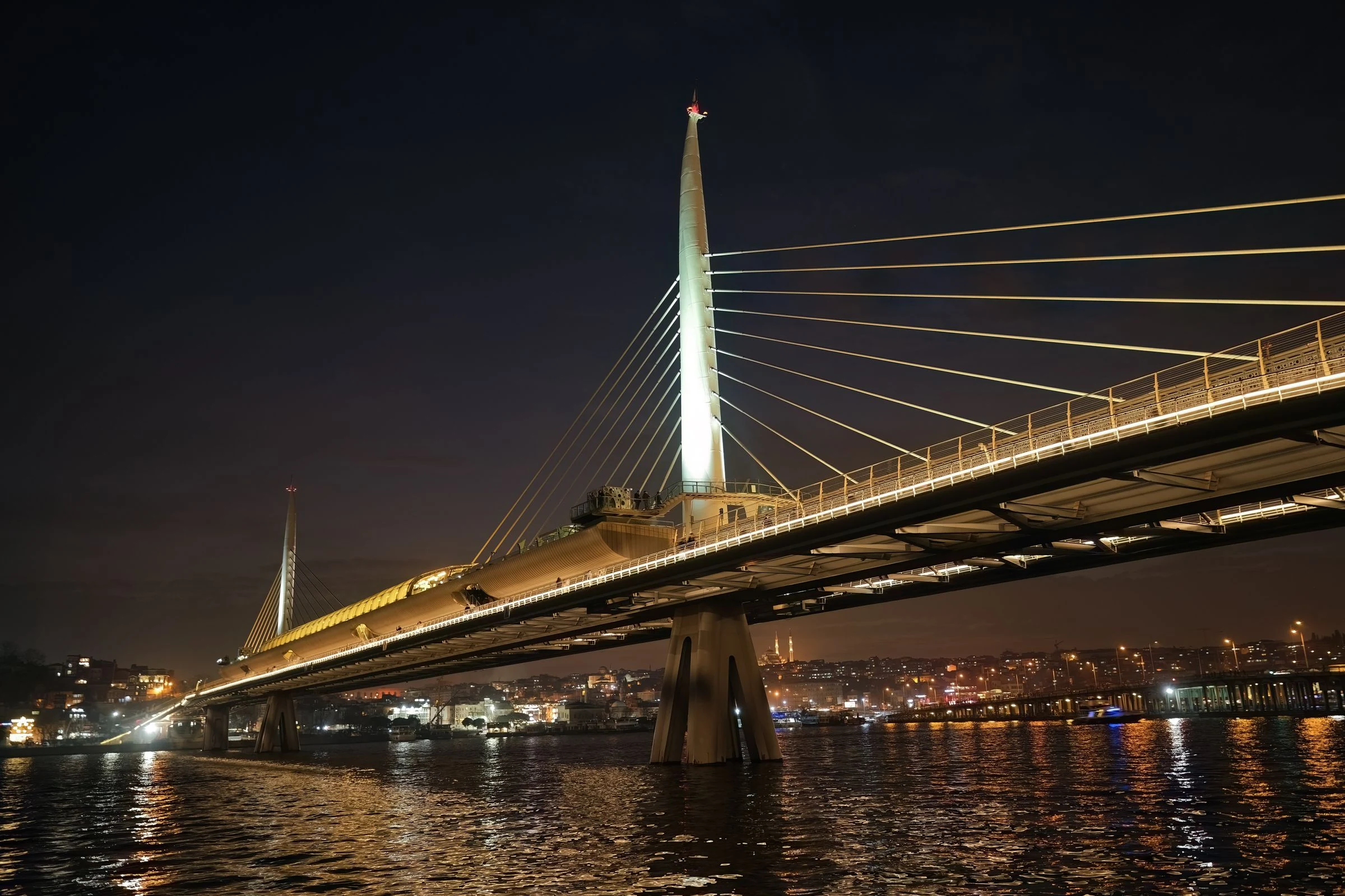 A cable-stayed bridge crossing a river at night.