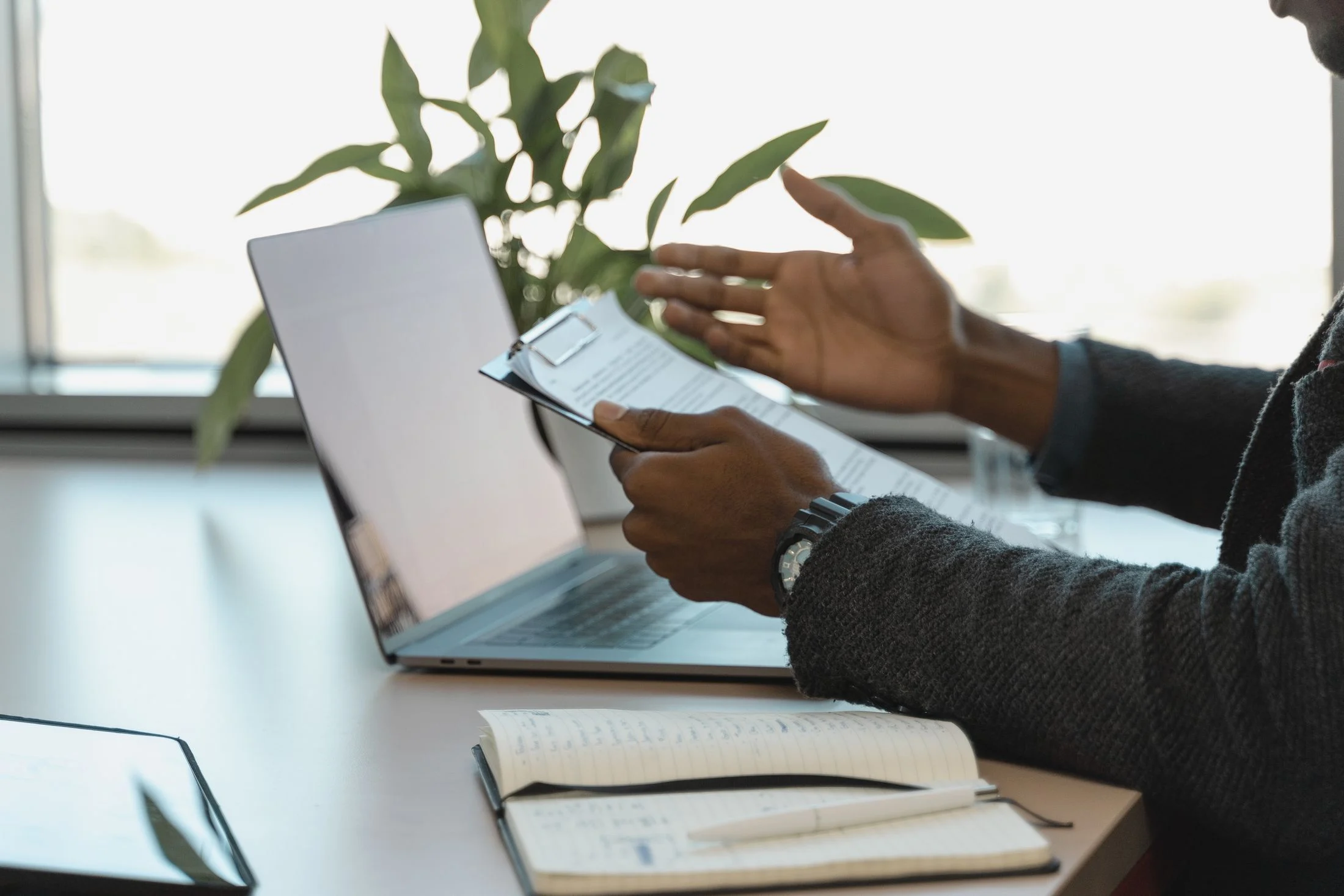 A person compares printed documents with information on a laptop.