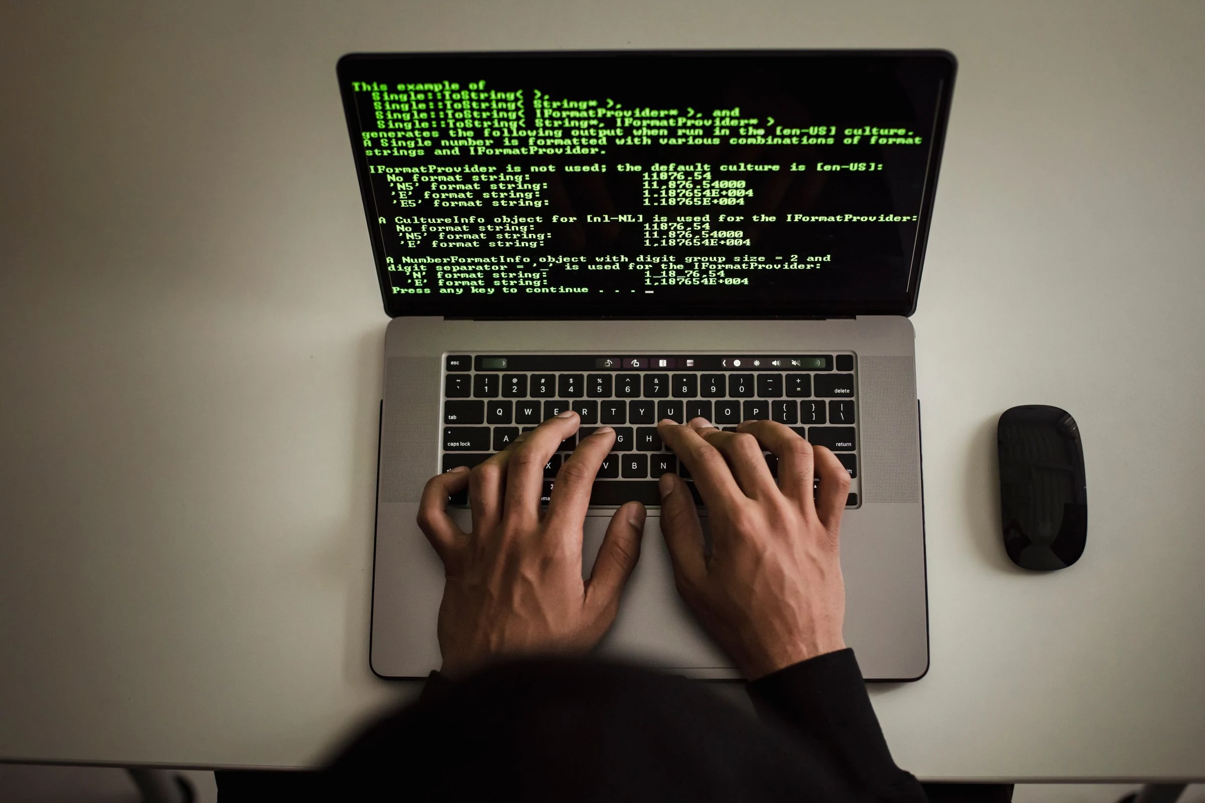 A developer working at a laptop with source code on screen.