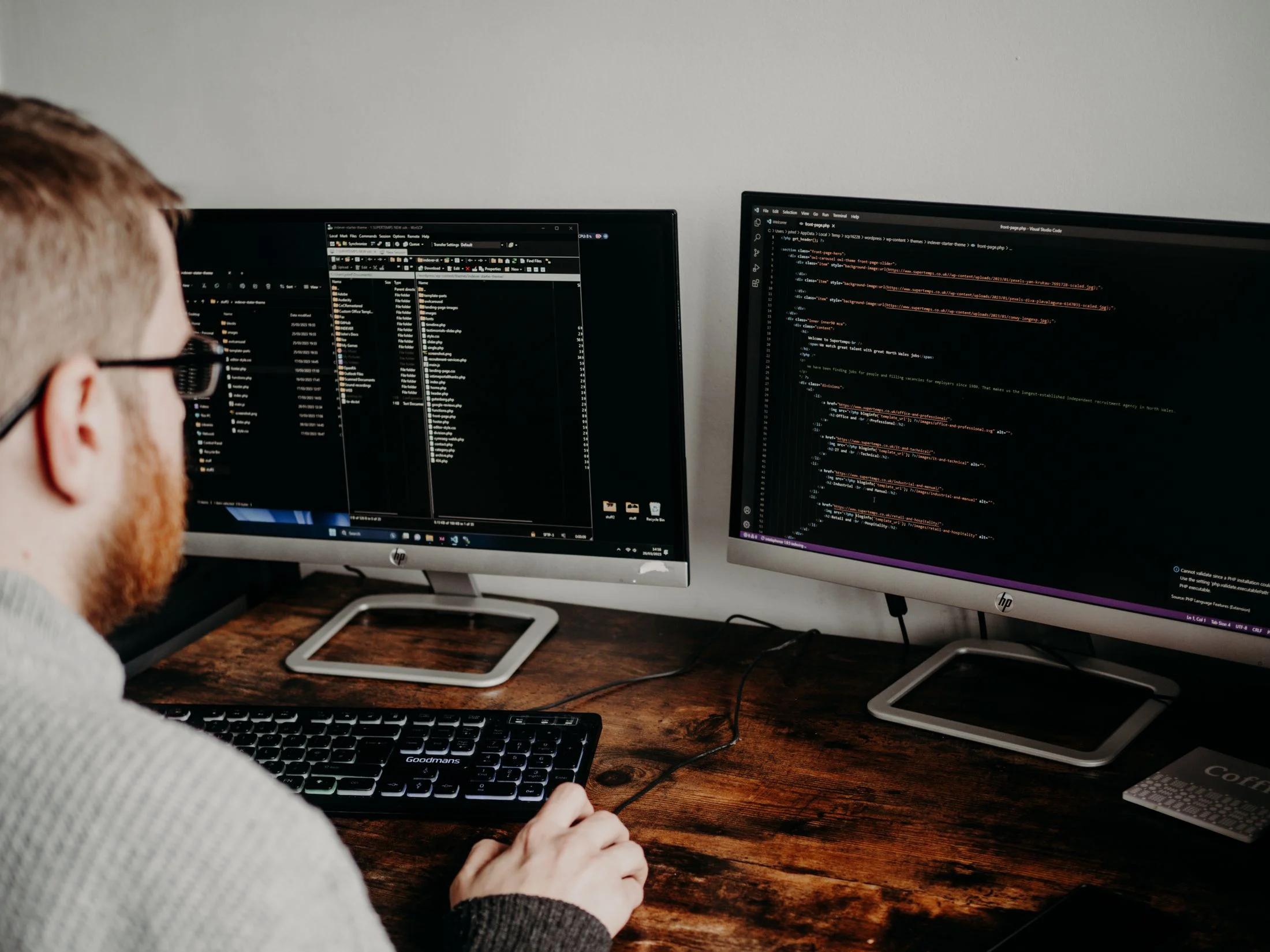 A software developer studies source code across two monitors.