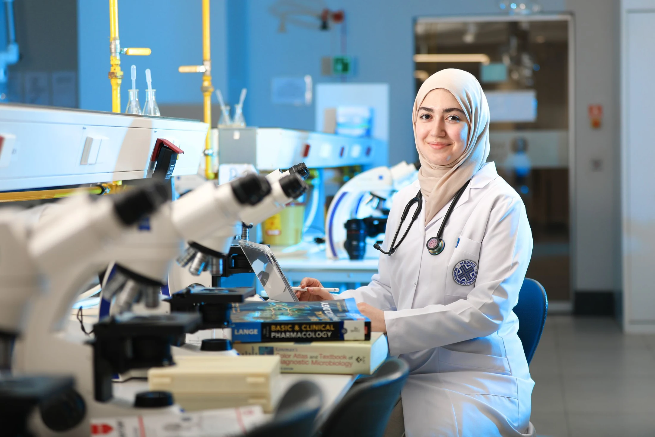 A scientist works beside a microscope in a bright research laboratory.