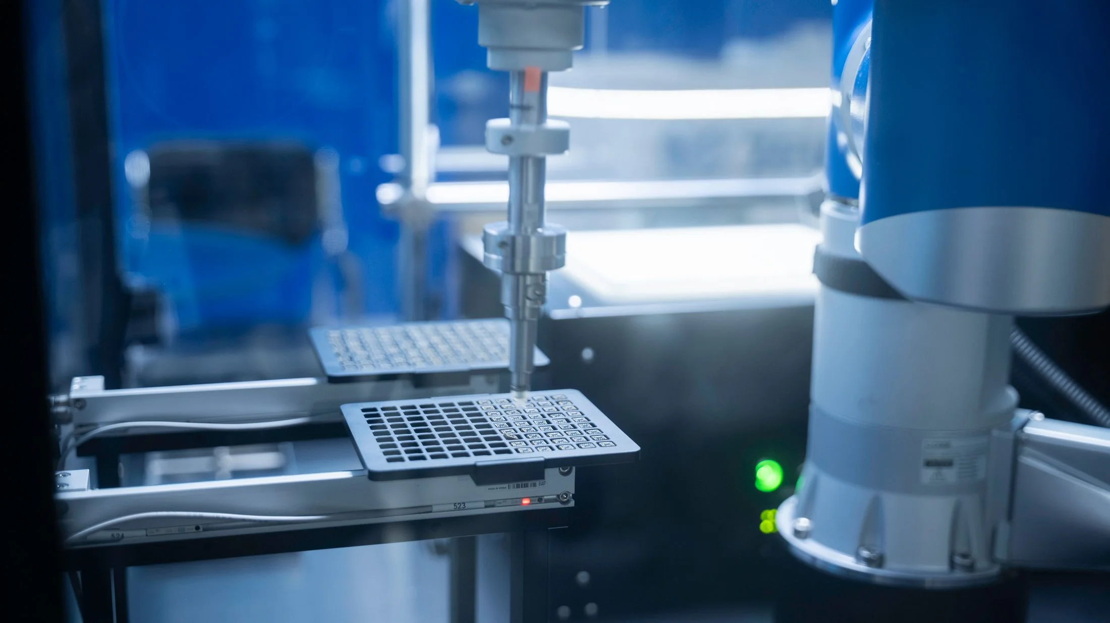 A close view of an industrial robotic arm working with a precise lab fixture.